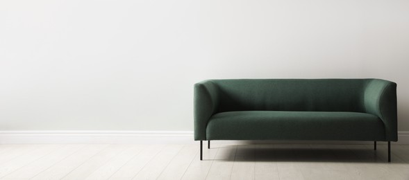 Comfortable green sofa near white wall indoors, space for text. Interior design