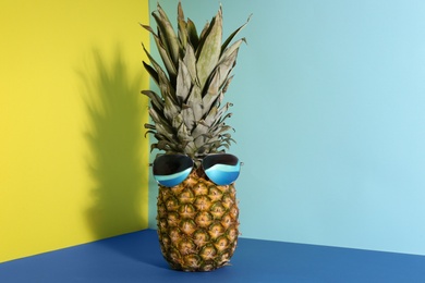 Photo of Pineapple with sunglasses on color background. Creative concept
