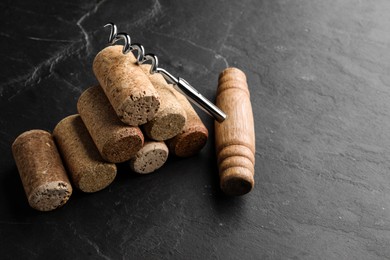 Corkscrew and stack of wine bottle stoppers on slate table