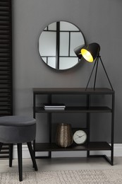 Console table with stool and mirror on grey wall in room. Interior design
