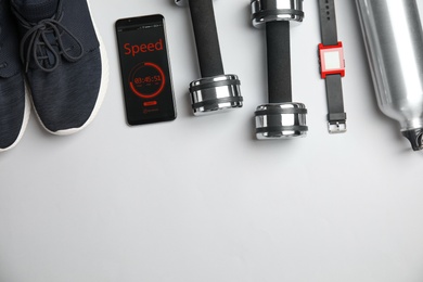 Photo of Smartphone with timer and fitness accessories on white background, flat lay. Space for text