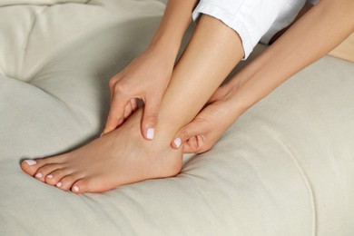 Woman rubbing sore foot on sofa, closeup