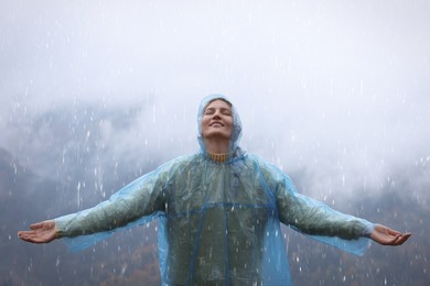 Photo of Young woman with raincoat enjoying rainy weather in mountains