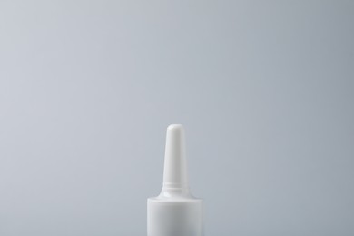 Bottle of nasal spray on grey background, closeup. Space for text