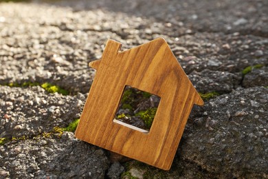 Wooden house model in cracked asphalt. Earthquake disaster