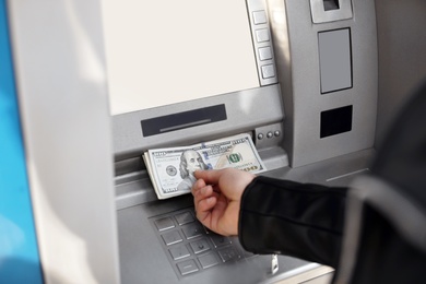 Man taking money from cash machine outdoors, closeup view