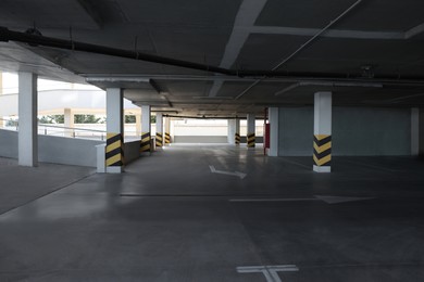 Empty open car parking garage with warning stripes on columns