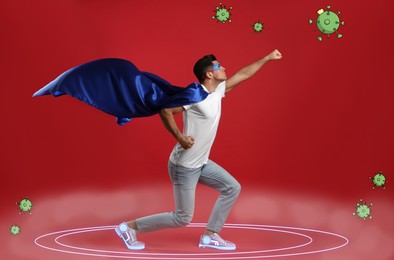 Man wearing superhero costume fighting against viruses on red background