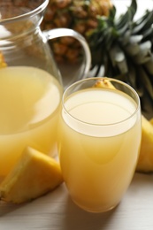 Photo of Delicious fresh pineapple juice on white wooden table, closeup