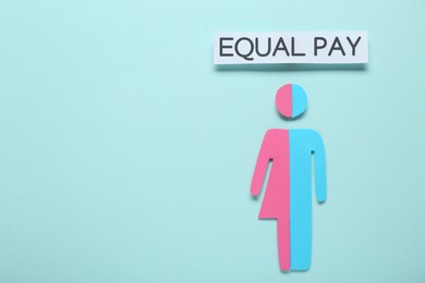 Photo of Equal pay concept. Human paper figure as male and female halves against light blue background, flat lay with space for text