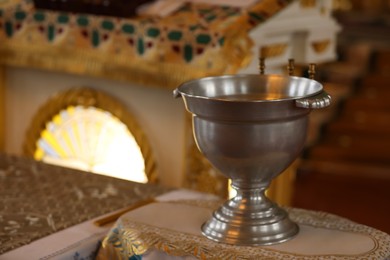Silver vessel with holy water on stand in church, space for text. Baptism ceremony