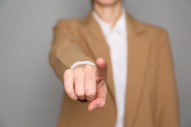 Businesswoman pointing at something on grey background, closeup. Finger gesture