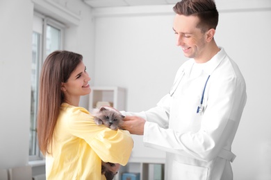 Young woman with cat and veterinarian in clinic