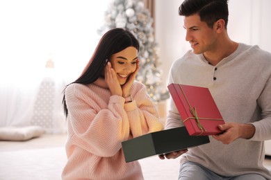 Couple opening gift box in room with Christmas tree