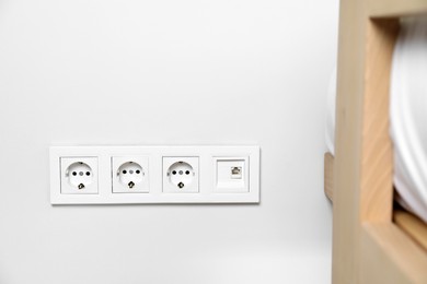 Power sockets on white wall indoors. Electrical supply