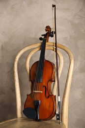Classic violin and bow on chair against beige background