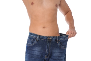 Fit man in oversized jeans on white background, closeup. Weight loss