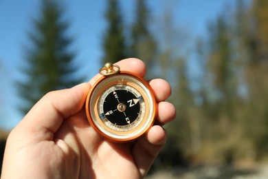 Photo of Man using compass for navigation during journey outdoors, closeup