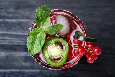 Photo of Spicy red currant cocktail with jalapeno and mint on black wooden table, top view