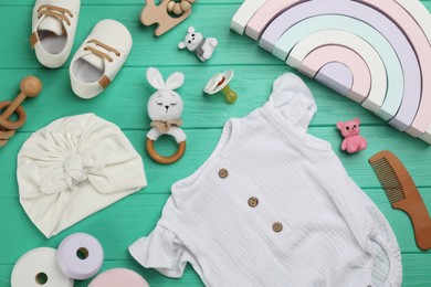 Flat lay composition with baby clothes and accessories on green wooden table