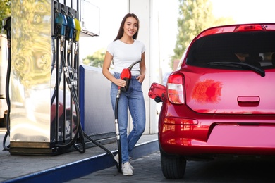 Photo of Young woman with fuel pump nozzle near car at self service gas station