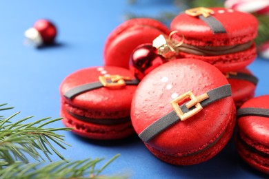Pile of beautifully decorated Christmas macarons on blue background, closeup. Space for text