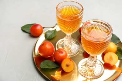 Delicious plum liquor and ripe fruits on light table. Homemade strong alcoholic beverage