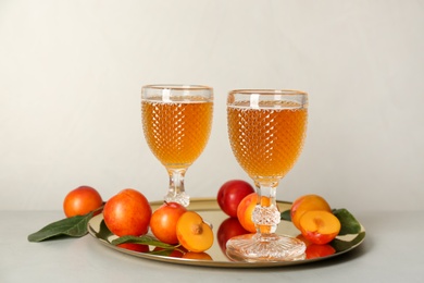 Delicious plum liquor and ripe fruits on light table. Homemade strong alcoholic beverage