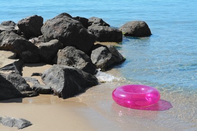 Photo of Bright inflatable ring on sandy beach near sea