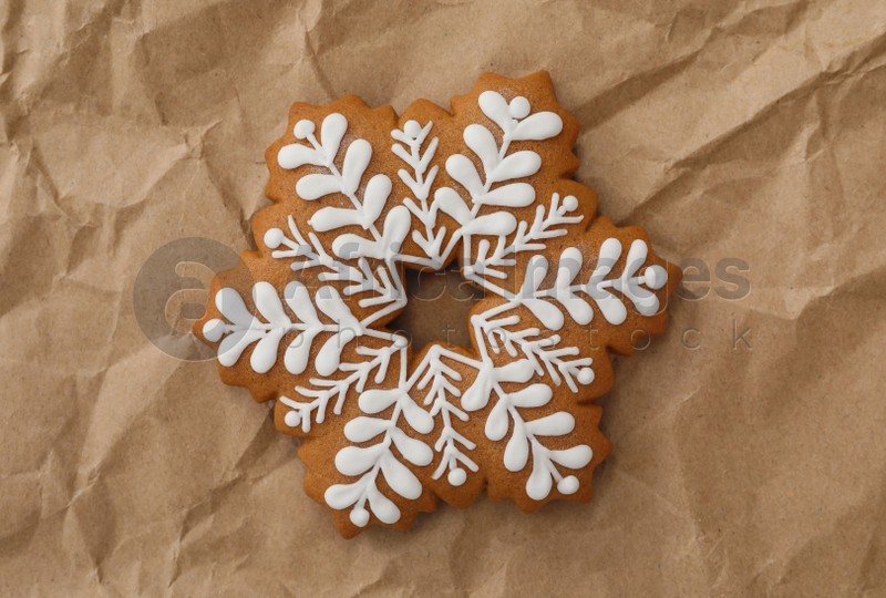 Christmas snowflake shaped gingerbread cookie on crumpled parchment, top view