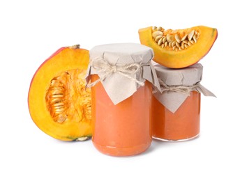 Jars of pumpkin jam and fresh pumpkin on white background