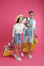 Couple of tourists with tickets, passports and suitcases on pink background