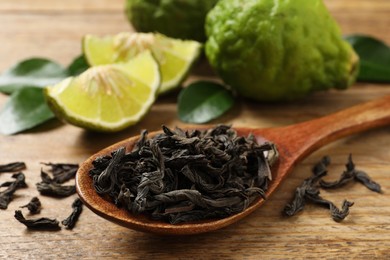 Dry bergamot tea leaves and fresh fruits on wooden table, closeup
