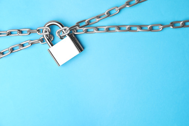 Steel padlock, chains and space for text on light blue background, top view. Safety concept