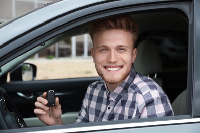 Attractive young man with key in modern car
