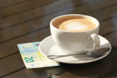 Photo of Tasty hot coffee and payment for order on table, closeup. Leave tip
