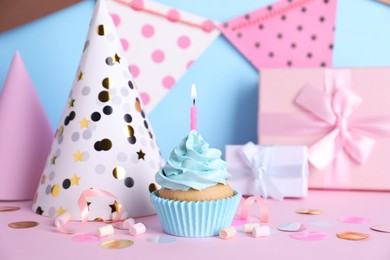 Delicious birthday cupcake with burning candle, marshmallows and party decor on color background