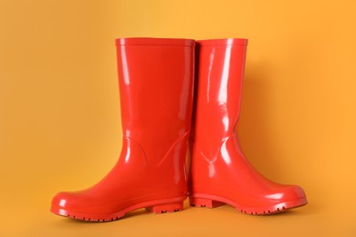 Pair of red rubber boots on orange background
