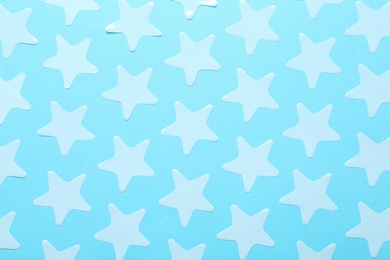 White star shaped confetti on light blue background, flat lay