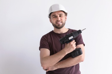 Young working man with electric screwdriver on white background