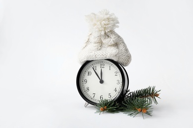 Photo of Alarm clock in hat and fir branch on white background. New Year countdown