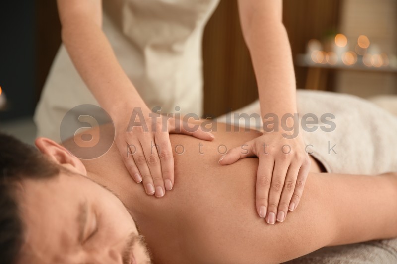 Photo of Handsome man receiving back massage in spa salon, closeup