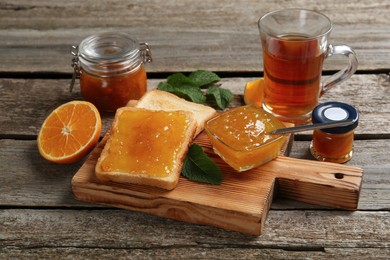 Delicious toasts served with jam and tea on wooden table