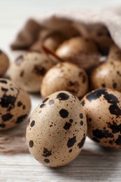 Fresh quail eggs on white wooden table, closeup