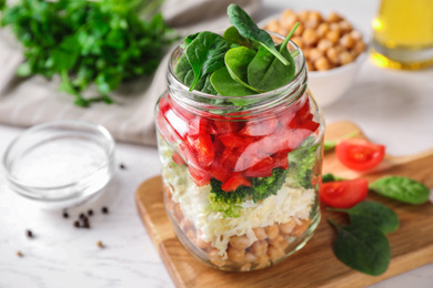 Healthy salad in glass jar on white table