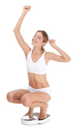 Happy young woman satisfied with her diet results using bathroom scales on white background