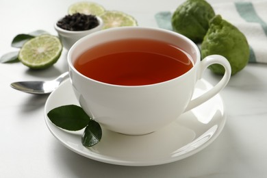 Cup of tasty bergamot tea on white table, closeup