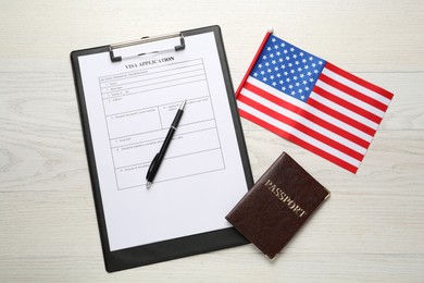 Photo of American flag, visa application form and passport on white wooden table, flat lay