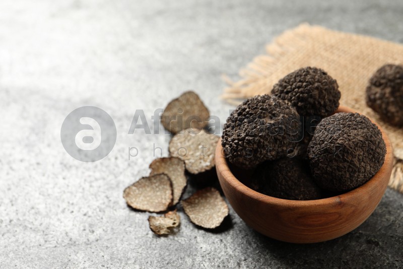 Black truffles with wooden bowl on grey table. space for text