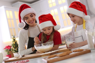 Mother with her cute little children making Christmas cookies in kitchen